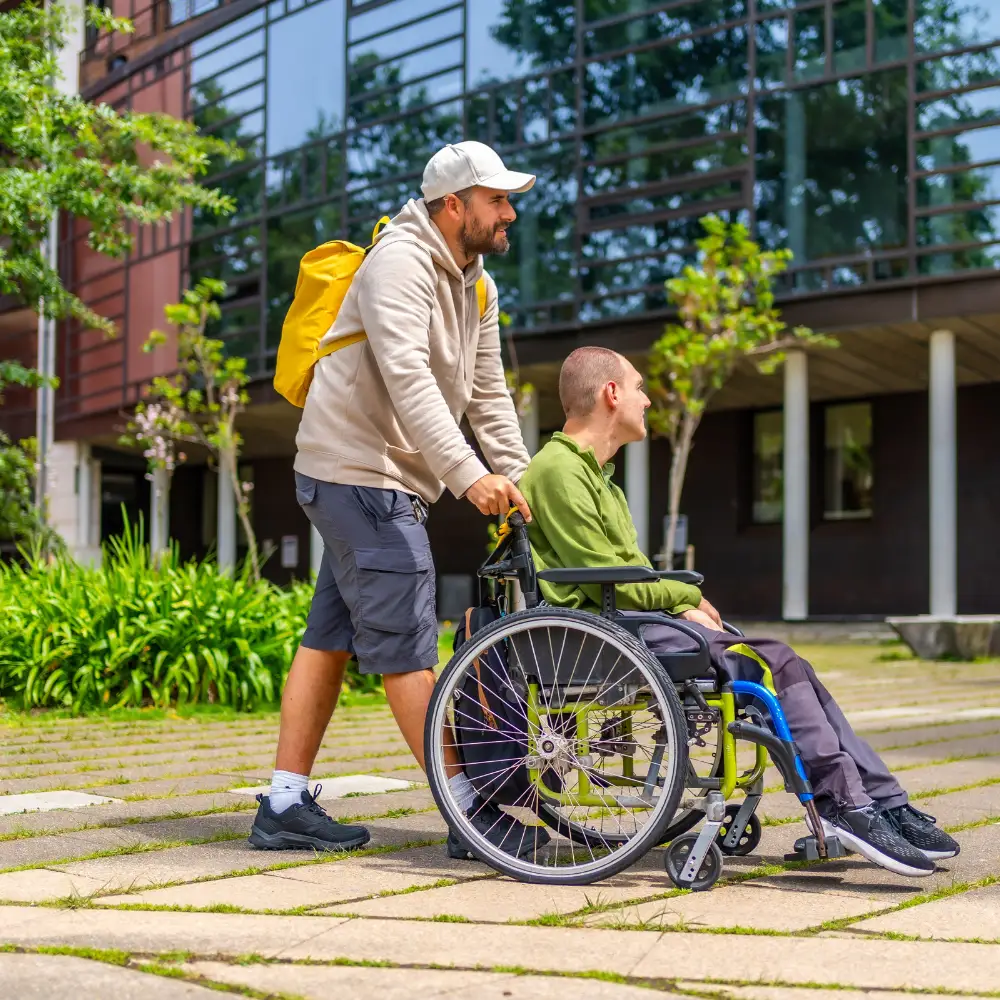 Disabled man in wheelchair being pushed by support worker