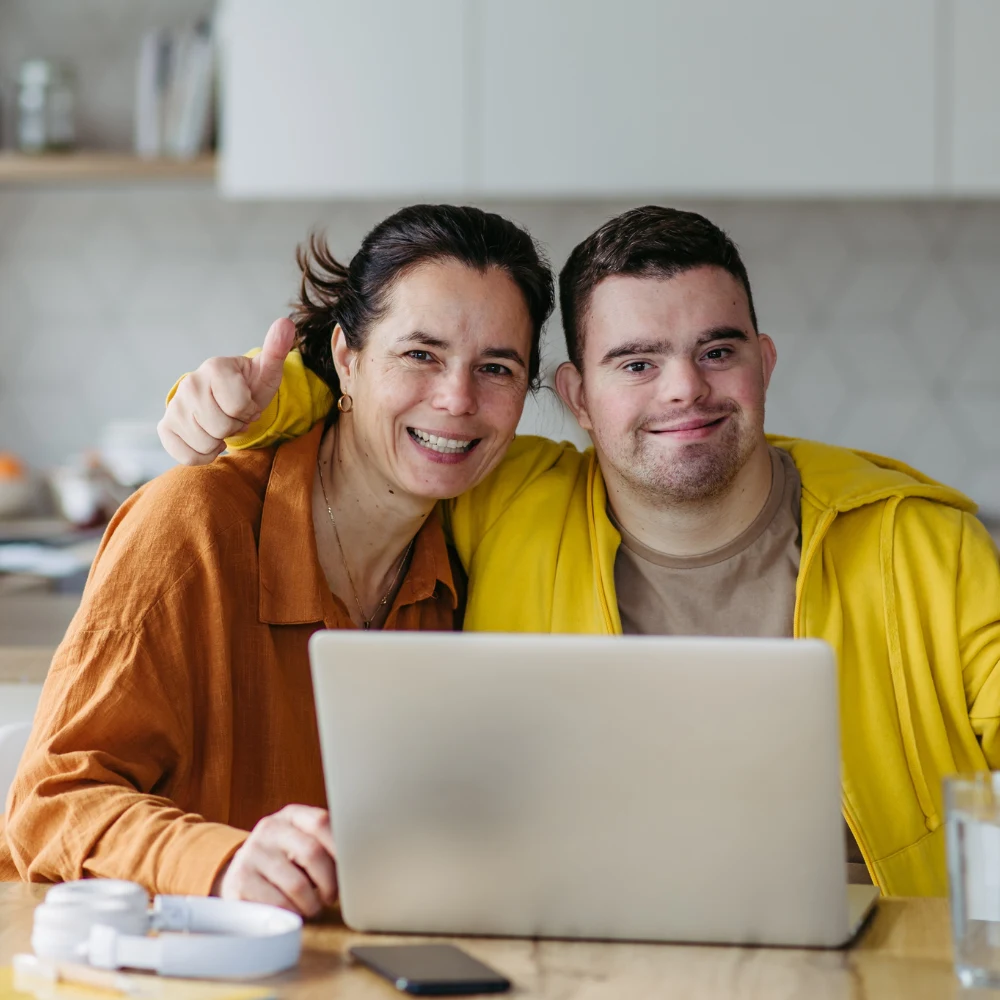 Disabled man with support worker both smiling at camera